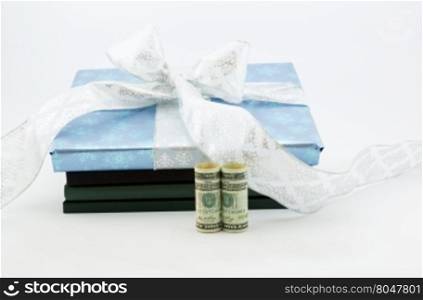 Gift wrapped book and lab notebooks placed with United States dollar currency reflects on wise investment in education and learning. Savings through 529 and College Savings Plans through gifting. Horizontal image with white background and copy space.