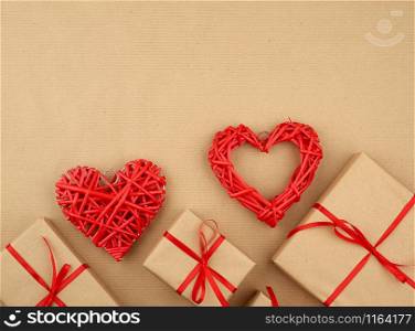 gift wrapped in brown kraft paper and tied with a thin silk ribbon on a background of paper, top view. Congratulations on Valentine&rsquo;s Day February 14, copy space