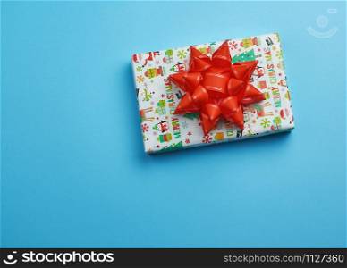 gift wrapped in multi-colored paper on a blue background, festive backdrop, top view, copy space