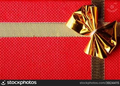 Giftbox closeup. Golden ribbon with bow for gift wrapping on red background