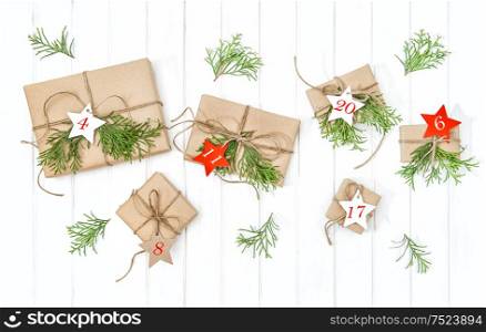 Gifts Advent calendar with christmas tree branches decoration on bright wooden background. Flat lay