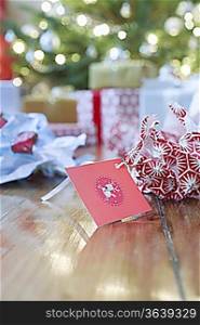 Gifts, unwrapped paper and gift tag on floor