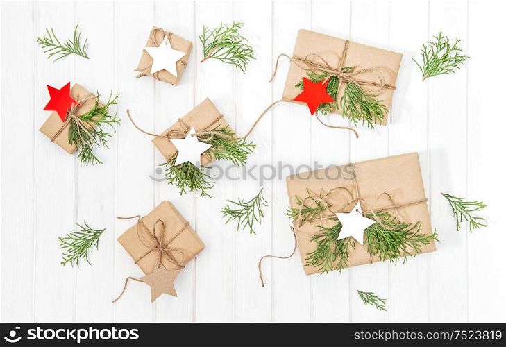 Gifts with Christmas tree branches decoration on bright wooden background. Flat lay