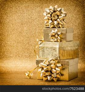 Gifts with ribbon bow on golden background. Holidays decoration. Vintage style toned picture