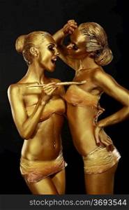 Gilt. Two Funny Women with Paintbrush. Futuristic Glossy Gold Make-up