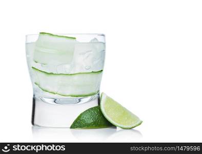 Gimlet cocktail in modern glass with ice cubes and straw, cucumber and lime slice on white background with limes on the side. Space for text