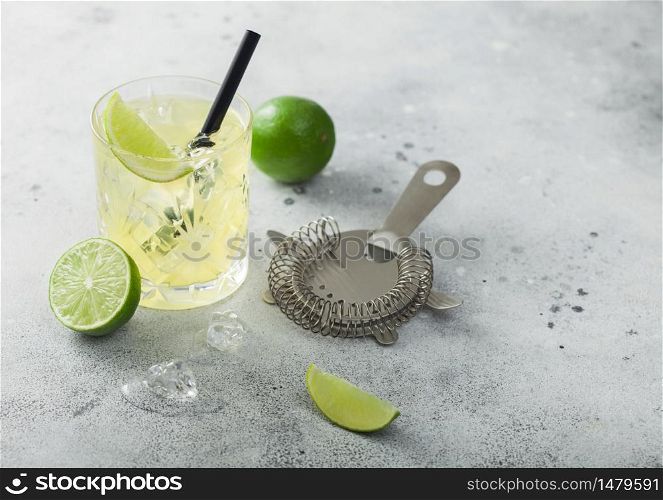 Gimlet Kamikaze cocktail in crystal glass with lime slice and ice on light background with strainer. Top view