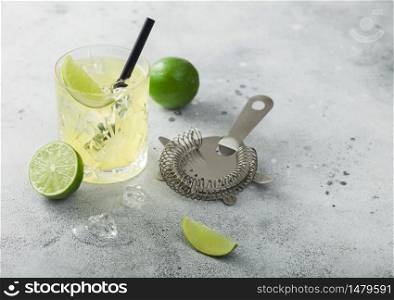 Gimlet Kamikaze cocktail in crystal glass with lime slice and ice on light background with strainer. Top view