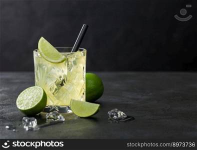 Gimlet Kamikaze cocktail in crystal glass with lime slice and ice on black background. Space for text