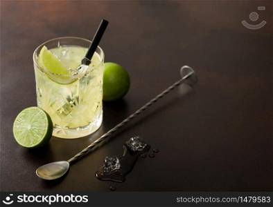Gimlet Kamikaze cocktail in crystal glasses with lime slice and ice on brown background with fresh limes and spoon. Top view