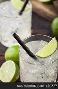 Gimlet Kamikaze cocktail in crystal glasses with lime slice and ice on wooden background. Macro