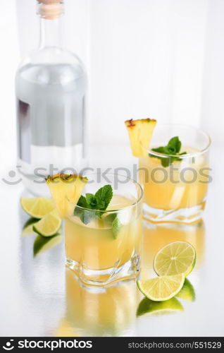 Gin cocktail with pineapple juice, a slice of lime, cooled with ice and mint