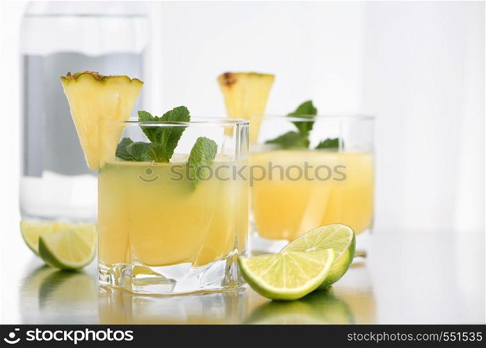 Gin cocktail with pineapple juice, a slice of lime, cooled with ice and mint