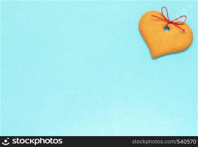 Ginger cookies heart-shaped decorated with a bow on a blue background. Top view Copy space Valentine card.. Ginger cookies heart-shaped decorated with a bow on a blue background. Top view Copy space Valentine card