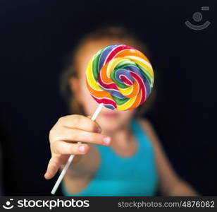 Ginger girl holding a sweet and colorful lollipop