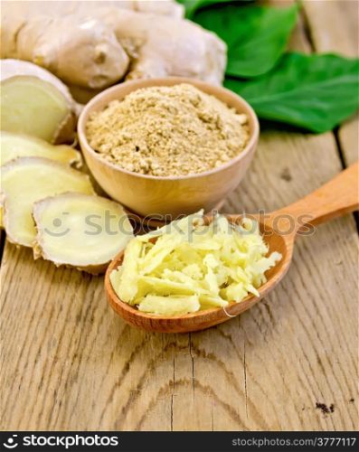 Ginger powder in a bowl, wooden spoon with grated ginger, ginger root, green leaves on the background of wooden boards