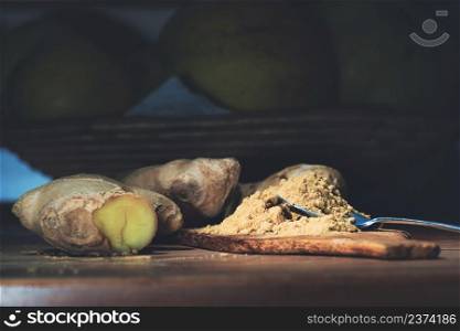 Ginger root and ginger powder on wood on wooden kitchen table
