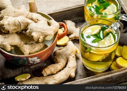 Ginger tea with mint and lemon. On wooden background.. Ginger tea with mint and lemon.