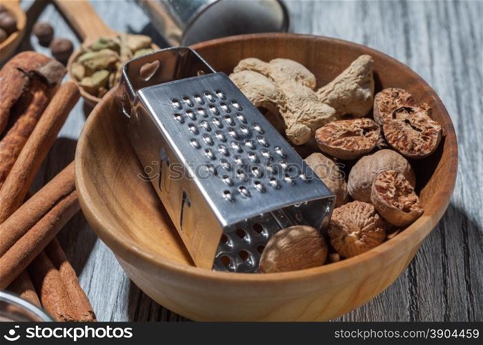 Ginger with nutmeg and grater in bowl on wooden background and various spices. Ginger with nutmeg and grater in bowl on wood
