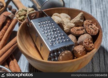 Ginger with nutmeg and grater in bowl on wooden background and various spices. Ginger with nutmeg and grater in bowl on wood