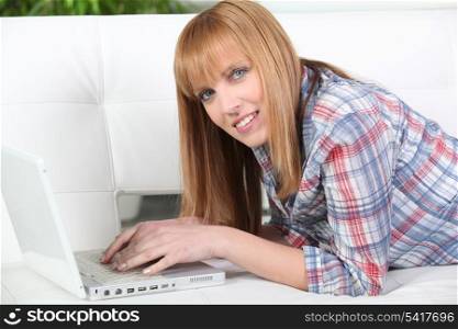 Ginger woman laid down using laptop