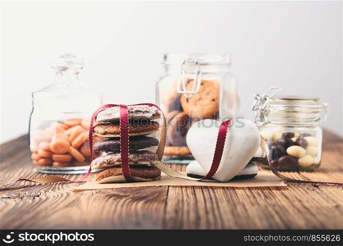 Gingerbread cookies, candies, cakes, sweets in jars on wooden table