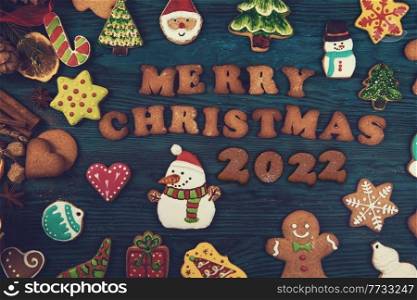 Gingerbread cookies for new 2022 year on wooden background, xmas theme. Brown sugar caramel candy cookies with a metal needle