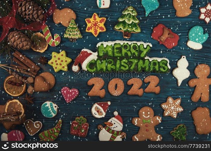 Gingerbread cookies for new 2022 year on wooden background, xmas theme. Brown sugar caramel candy cookies with a metal needle