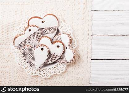Gingerbread cookies in shape of heart with icing on a crochet doily. Set of homemade cookies