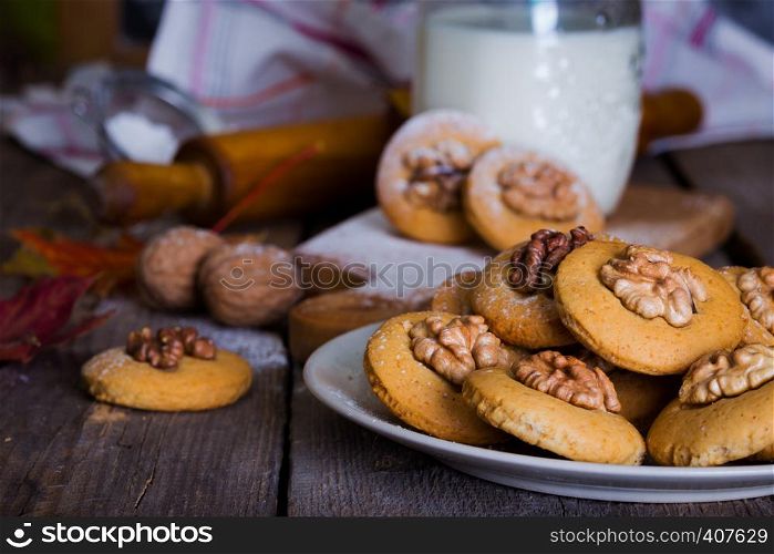 gingerbread cookies with walnuts on a table and a cup of milk