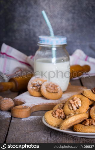 gingerbread cookies with walnuts on a table and a cup of milk