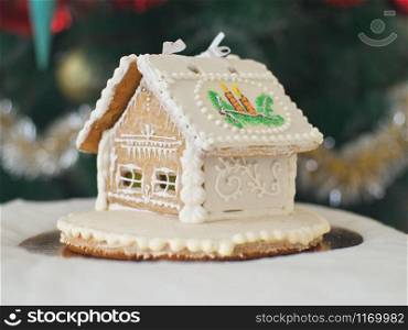 Gingerbread house over defocused lights of Chrismtas decorated fir tree