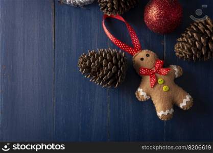 gingerbread man felted figurine with Pine cones and red christmas balls for christmas decoration on vintage blue wood background. Copy space for your text