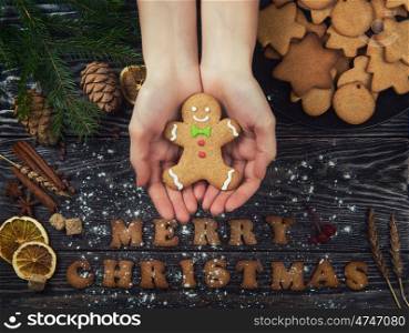 Gingerbreads for new years and christmas. Woman hands keep gingerbreads for new years and christmas on wooden background with space for design