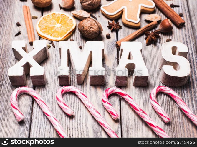 Gingerbreads with spices on the wooden table, wooden letters XMAS and Santa staffs candies. Christmas aroma decor