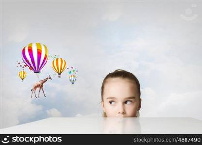 Giraffe flying on balloons. Little cute girl looking from under the table