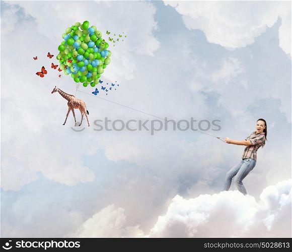 Giraffe on lead. Young woman in casual and giraffe flying in sky