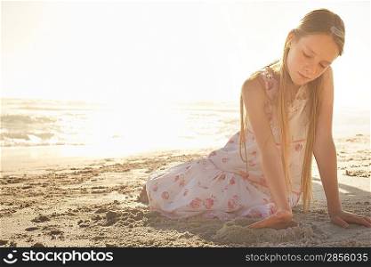 Girl (10-12) playing in sand on beach at sunset