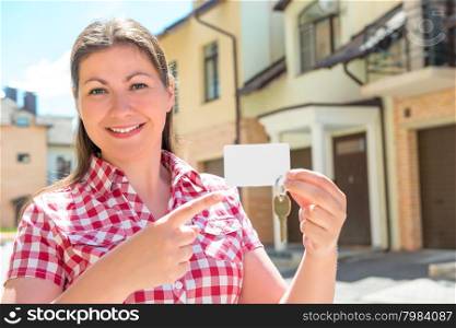 Girl 30 years old smiles and points to the key to the apartment