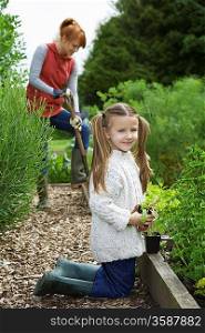 Girl (5-6) gardening with mother in countryside