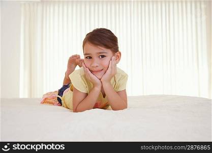 Girl (5-6) lying on bed