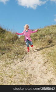 Girl (5-6) running down sand dunes