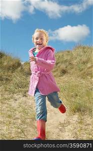 Girl (5-6) running down sand dunes