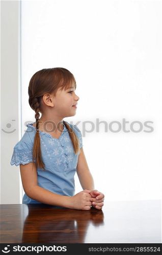 Girl (5-6) sitting at table profile