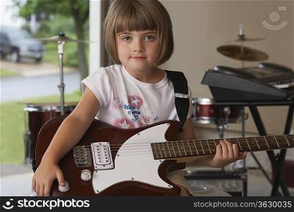 Girl (5-6) sitting in garage with guitar