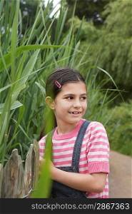 Girl (5-6) standing beside reeds