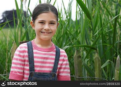 Girl (5-6) standing beside reeds, portrait