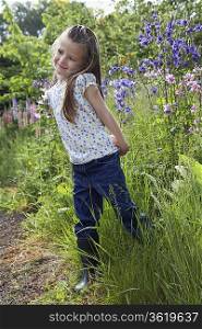 Girl (5-6) standing in garden