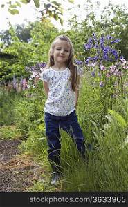 Girl (5-6) standing in garden, portrait