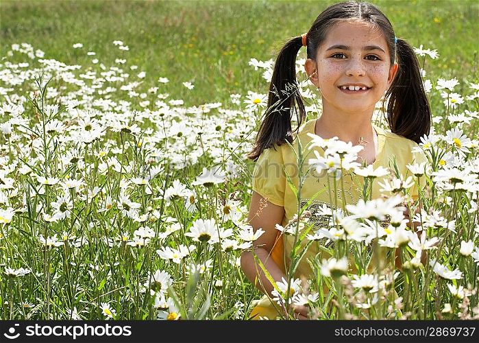Girl (7-9) holding flowers in meadow, portrait